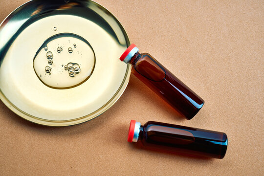 Skincare oil drops in petri dish with serum vials