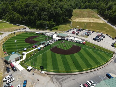 Youth baseball game on turf field in rural Appalachian mountains with families and community setting