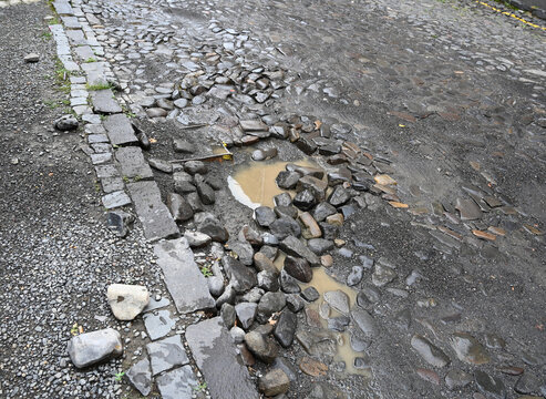 Puddle forms in cobblestone street after rain in urban area