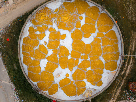 Aerial view of a circular structure with golden hues contrasting against a white backdrop, creating a mosaic of color and texture, Avezzano, Abruzzo, Italy.