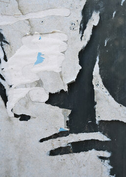 Peeling layers of paint on a wall showing abstract patterns in an urban setting during daytime