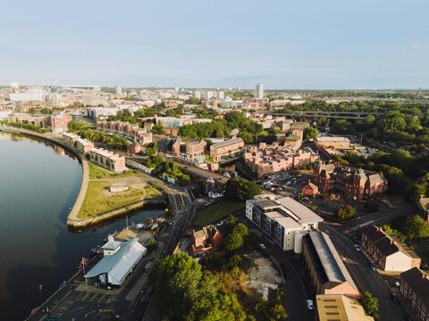 Newcastle upon Tyne: 9th August 2025: Mouth of the Ouseburn joins the River Tyne in Newcastle with buildings and waterfront pathway during clear weather. Drone view