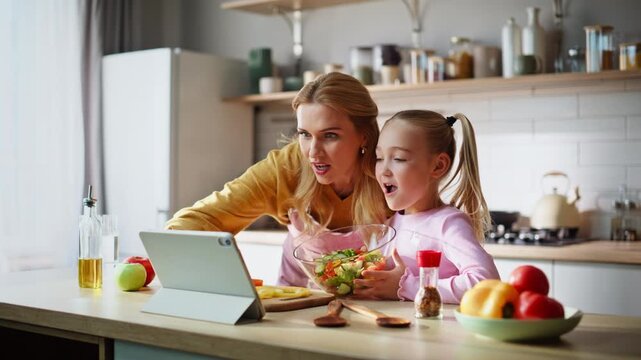 Mother daughter using tablet sharing video conversation in cozy kitchen closeup
