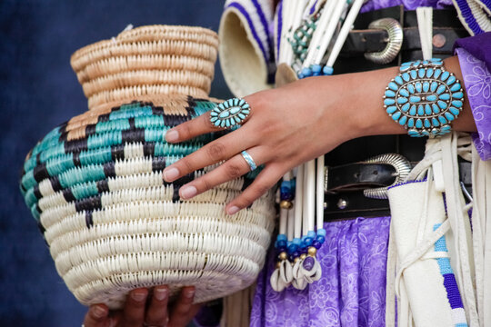 Santa Fe, New Mexico, USA. Indian Market, Native American woman holding a basket and wearing turquoise jewelry 
