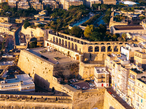 Aerial view of the golden-hued Fort Saint Elmo standing proudly against the azure sky, its ancient stone walls whispering tales of history, Valletta, Malta.
