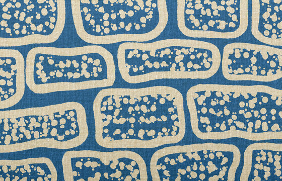 Blue fabric texture with abstract beige pattern and random speckles creating a contemporary background design