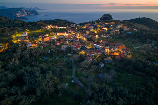 Beautiful aerial drone shot of Krini village nestled in olive groves with Angelokastro castle and colorful sunset sky in Corfu island Greece