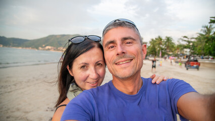 Tourists take a selfie with the senic view of Patong Beach at sunset with palm trees and vibrant reflections