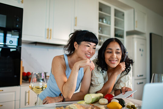 Smiling women cooking dinner together at modern home kitchen