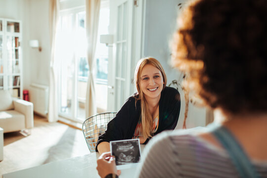 Friends sharing pregnancy ultrasound at home