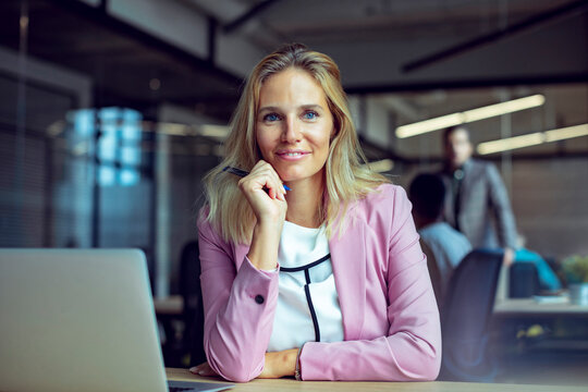 Confident businesswoman with laptop in modern office
