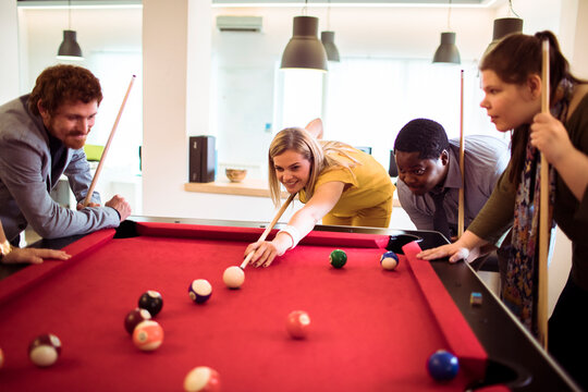 Coworkers playing billiards during office break
