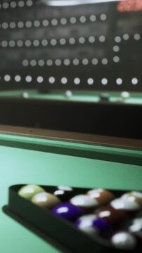 Players engage in a game of billiards at a pool table. The setting features a green felt surface and colorful balls arranged in a rack. This scene captures the social aspect of playing billiards.