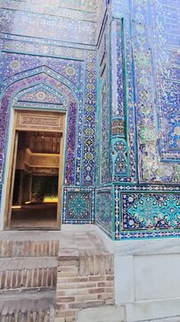 Circling video of three opposing mausoleums in golden sunbeams at Shah-i-Zinda. Brilliant blue, turquoise glazed tiles, detailed geometric designs. Historic Islamic architecture Samarkand, Uzbekistan.