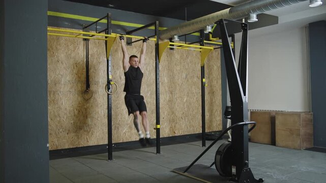 Man performs pull-up exercise on barbell in a gym setting during a workout session