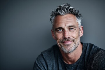 Obraz premium Portrait of a smiling man in his 50s smiling at the camera over soft gray background