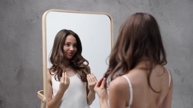 Cute woman admiring herself in the mirror, enjoying smooth skin and natural beauty. Skincare and self-care concept.
