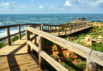 Fototapeta premium Wooden boardwalk leading to ocean viewpoint on portugal's atlantic coast