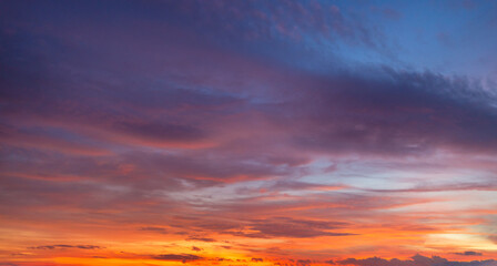 Obraz premium Vibrant Sunset Sky with Rich Orange, Pink, and Purple Clouds,A stunning panoramic photograph capturing the dramatic color palette of a sunset sky. The scene is dominated by a gradient of fiery orange 