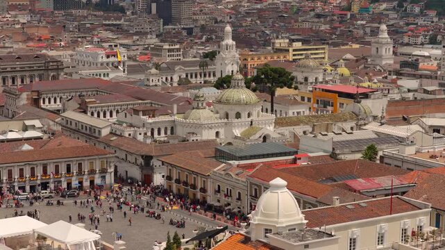 Drone aerial view of La Compania de Jesus church with its distinctive green dome, located in the historic center of Quito, Ecuador, surrounded by colonial buildings and narrow streets.