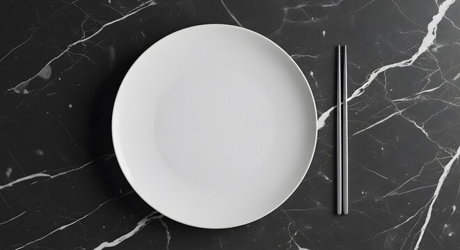 A minimalist white ceramic dinner plate placed on a sleek dark marble surface with metal chopsticks
