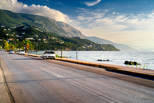 Coast Greek island Corfu with cars and mountains in morning light.