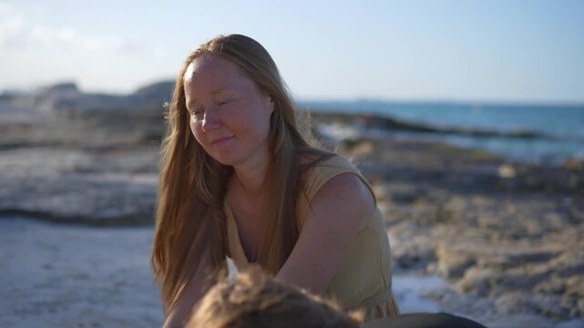 Young mom spending quality time with her two sons on a beautiful tropical beach, enjoying sunshine, laughter, and family bonding moments by the sea.