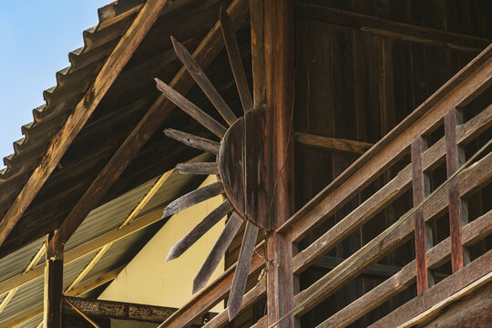 Old traditional wooden house balcony featuring unique sunburst wood carving decoration and designed to prevent people from climbing over balcony. Sunburst design by wood craft. Traditional lifestyle