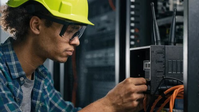 Medium shot of telecom technician swapping SIM cards in an LTE backup device while the rest of the rack remains out of focus illustrating mobile network redundancy.