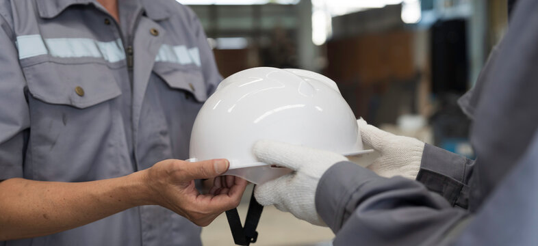 Hands of team worker holding helmet at factory