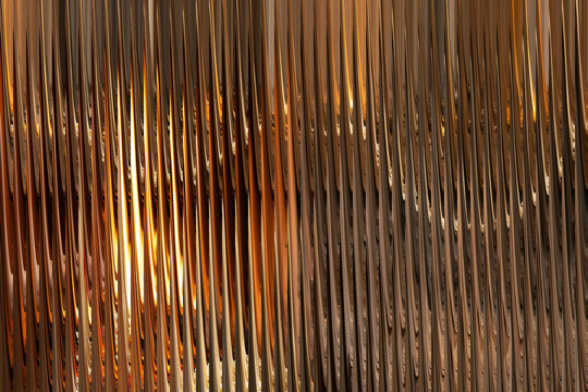 Abstract vertical parallel lines of textured material create a shimmering golden brown ribbed background texture.
