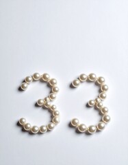 Obraz premium Number 33 made out of small pearls on a neutral solid background