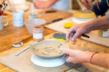 Obraz premium Female artisan decorating ceramic plate with hand-painted patterns in workshop