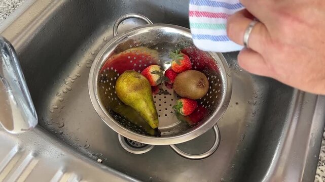 Manos secando una fresa con un trapo de cocina