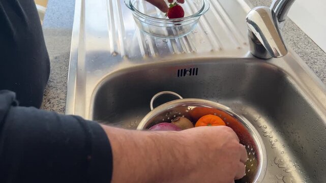 Manos pasando frutas del escurridor a un bol de cristal