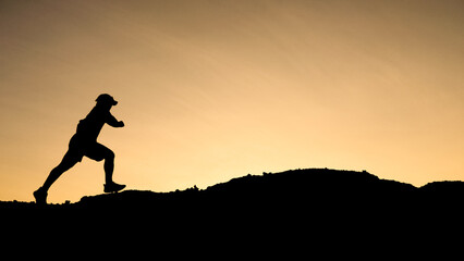 Silhouette of a runner conquering a hill against a warm sunset. Capture the energy and...