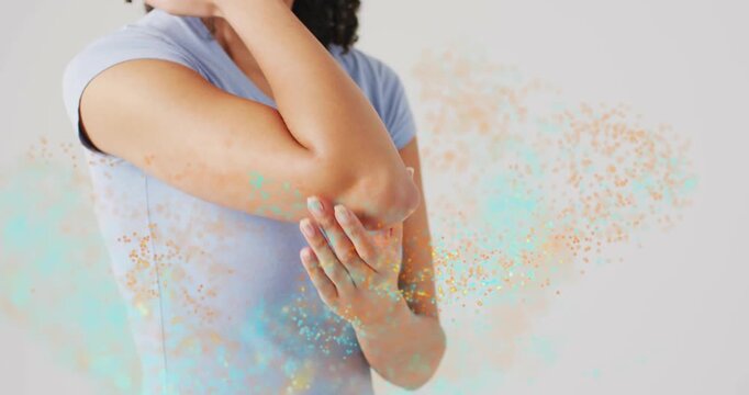 Woman sensing elbow pain massaging left elbow for health while turquoise gold dust flowing relaxing