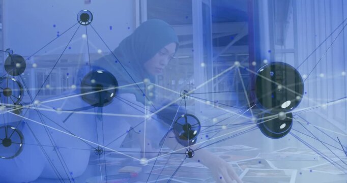 Scanning pages, woman in hijab arranging prints on workroom desk, organizing with digital overlay