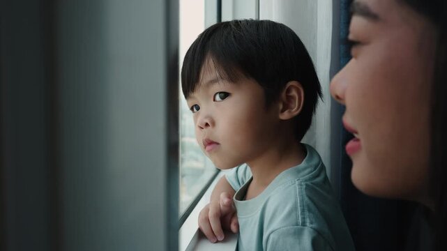 Mother and son looking out the window contemplating the city from a skyscraper
