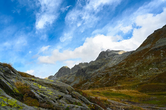 On the journey, a view from the Spl&uuml;gen Pass in the Alps, with the Via Spluga leading to the Surettahorn in Switzerland, featuring valleys, other peaks, and mountain panoramic scenery.