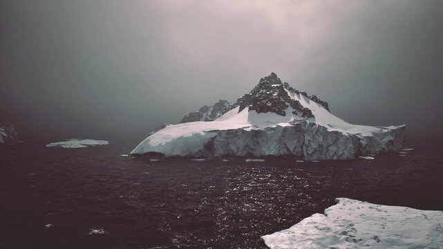 Overcast light highlights icy ridge structures. Shaded contours and textured ice in foreground enhance perception of rugged distant mountain range