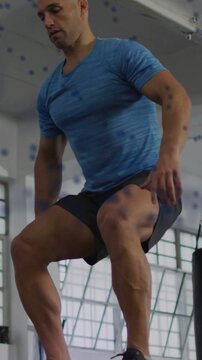 Fit man preparing at plyo box, driving legs and jumping onto box, landing for fitness training