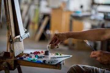 Fototapeta premium Man working in art studio mixing solvent for oil painting. Artist preparing canvas for creative project.