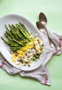 Asparagus salad Mimosa. Spring and Easter salad with grated egg, capers and aromatic dressing. Sunlight background. Healthy vegetarian balanced recipes for spring, seasonal cuisine 
