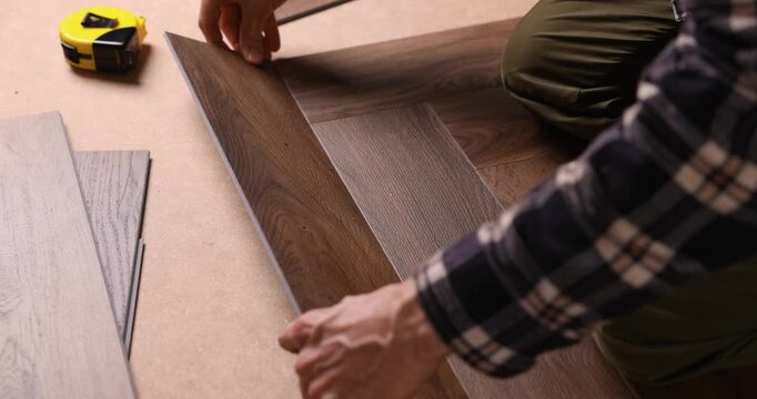 worker installing new vinyl tile wood texture flooring in a herringbone pattern
