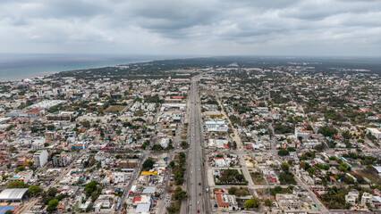 Obraz premium Aerial cityscape drone panoramic view of Playa del carmen with large highway crossing the city and Caribbean Sea in the background on a cloudy day in the Riviera Maya