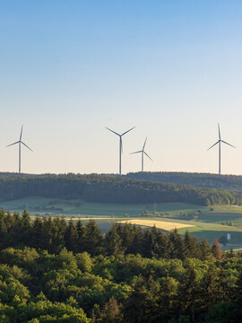 Wind turbines on hill above rural landscape, renewable energy in Germany