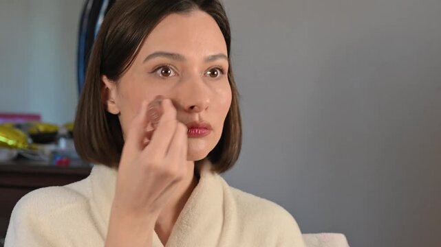 Young woman doing makeup at home, applying blush