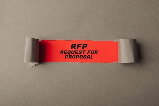 Bright orange paper strip with bold black text stating RFP, request for proposal, on a gray background, symbolizing business communication and project management
