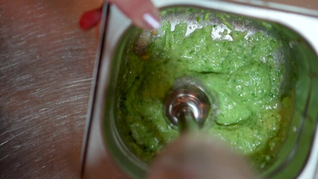 A chef in a restaurant prepares basil sauce